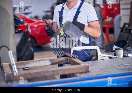 Uomo che tiene la torcia di saldatura e il casco di saldatura Foto Stock