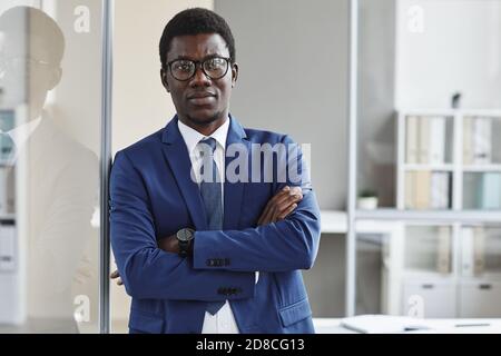 Ritratto di leader africano fiducioso in tuta guardando la fotocamera mentre si è in ufficio Foto Stock