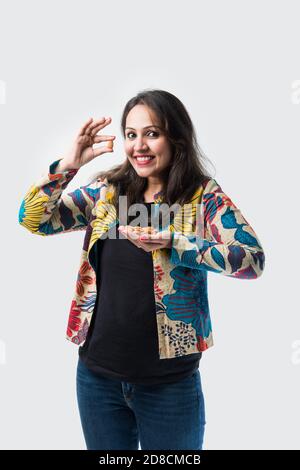 Bella ragazza indiana asiatica giovane mostrando frutta secca come Cashew, mandorla o noce - sano concetto di consumo Foto Stock