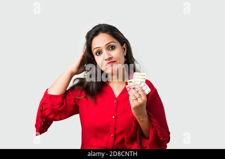 Medicina. Bella sorridente indiano asiatico donna che tiene Blister Pack con le pillole in mano. Ragazza asiatica con tablet che mostrano lo schermo mobile Foto Stock