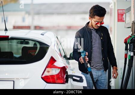 Uomo del Sud asiatico o maschio indiano che rifornisce la sua auto bianca sulla stazione di servizio. Foto Stock