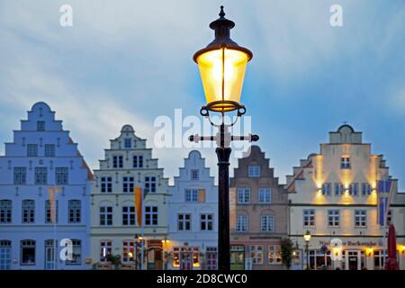 Lanterna storica di fronte alle case a timpano nella piazza del mercato in serata, Germania, Schleswig-Holstein, Frisia settentrionale, Friedrichstadt Foto Stock