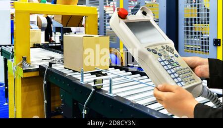 Il responsabile controlla e controlla le scatole di cartone automatiche sul nastro trasportatore nel magazzino di distribuzione. Foto Stock