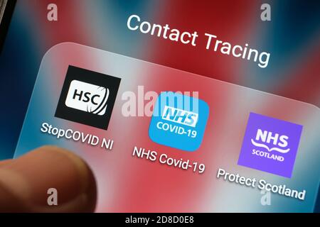 L'app NHS COVID-19 del Regno Unito e altre applicazioni di tracciamento dei contatti sono visualizzate su uno schermo e puntano le dita sfocate. Foto Stock