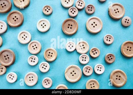 molti grandi e piccoli bottoni di legno beige su sfondo blu Foto Stock