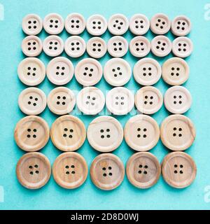 gruppo di grandi e piccoli bottoni di legno beige in fila su sfondo blu Foto Stock