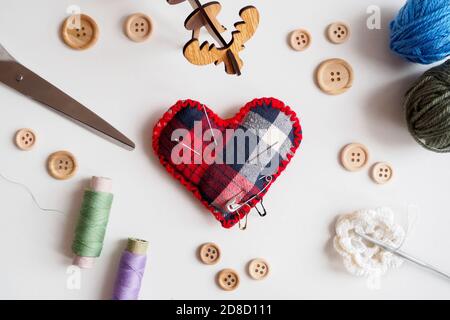 kit da cucire con filo, forbici, bottoni e cuscino ad ago su fondo bianco, piatto Foto Stock