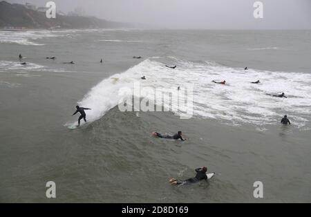 I surfisti si godono le grandi onde nel mare al largo della spiaggia di Bournemouth in Dorset. Il Met Office ha avvertito che i downpour torrenziali sono previsti per portare 'infuori' in tutto il Regno Unito con grandi onde, pioggia pesante, forti galee e potenziali inondazioni fluviali che colpiscono la costa occidentale dell'Inghilterra, gran parte del Galles e parti della Scozia da giovedì. Foto Stock