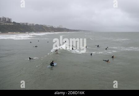 I surfisti si godono le grandi onde nel mare al largo della spiaggia di Bournemouth in Dorset. Il Met Office ha avvertito che i downpour torrenziali sono previsti per portare 'infuori' in tutto il Regno Unito con grandi onde, pioggia pesante, forti galee e potenziali inondazioni fluviali che colpiscono la costa occidentale dell'Inghilterra, gran parte del Galles e parti della Scozia da giovedì. Foto Stock