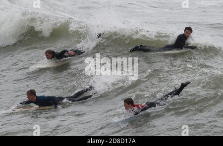 I surfisti si godono le grandi onde nel mare al largo della spiaggia di Bournemouth in Dorset. Il Met Office ha avvertito che i downpour torrenziali sono previsti per portare 'infuori' in tutto il Regno Unito con grandi onde, pioggia pesante, forti galee e potenziali inondazioni fluviali che colpiscono la costa occidentale dell'Inghilterra, gran parte del Galles e parti della Scozia da giovedì. Foto Stock