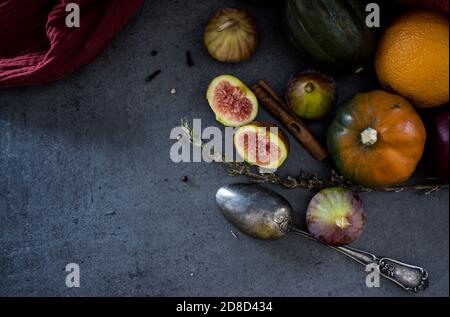 Frutta fresca e verdure su un tavolo. Zucca gemma, prugne, fichi e cucchiaio d'argento su sfondo grigio. Vista dall'alto della vendemmia autunnale. Foto Stock