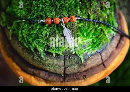 Pendente in piuma di metallo con bracciale con perline di semi di rudraksha su muschio polipo Foto Stock