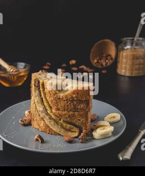 Pane di noce di banana fatto in casa posto sul piatto. Vista frontale, primo piano. Una consistenza di pane dolce e appetitosa, con nocciole schiacciate e aroma di miele. Foto Stock