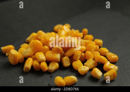 cibo di fondo dolce zucchero giallo mais sdraiato in un mucchio su uno sfondo grigio scuro roccioso, vista laterale dello spazio di copia Foto Stock