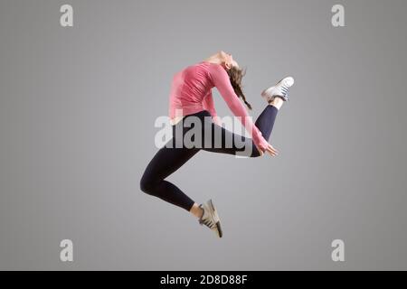 Ritratto della ballerina moderna che salta in aria parete grigia Foto Stock