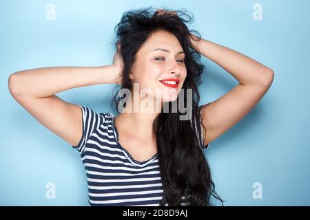 Ritratto di giovane donna spensierata sorridente con mani in capelli Foto Stock