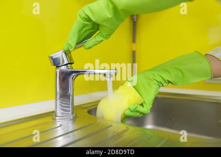 Primo piano della cucina di pulizia, mani della donna in guanti di gomma con spugna Foto Stock