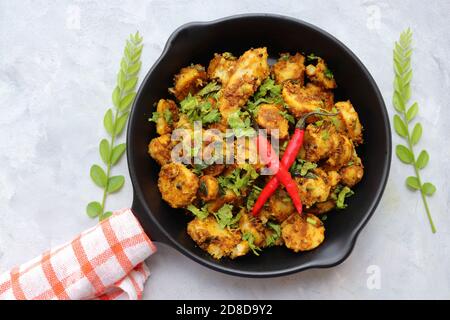 Mescolare le radici di taro fritte. Arbi ki sabji, Taro radici masala curry. Arbi Masala. Guarnito con coriandolo, peperoncino rosso e foglie di curry. Copia spazio. Foto Stock