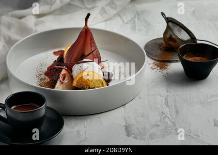 Pera affogata con un gelato in salsa di vino rosso Foto Stock