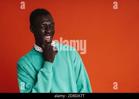 Uomo afroamericano pensivo sorridente indossando abbigliamento casual isolato sopra sfondo rosso Foto Stock