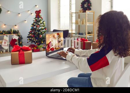 Bambina seduto al tavolo e con videochiamata Babbo Natale che sta leggendo la sua lettera Foto Stock