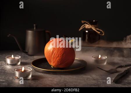 Modello vintage con stoviglie in metallo, zucca matura e orecchio di grano su fondo in pietra nera per il design concettuale. Concetto di caduta. Concetto di design degli interni. Foto Stock