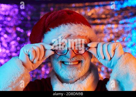 Primo piano di uomo bearded in cappello di Santa indossando occhiali e. sorridendo alla macchina fotografica Foto Stock