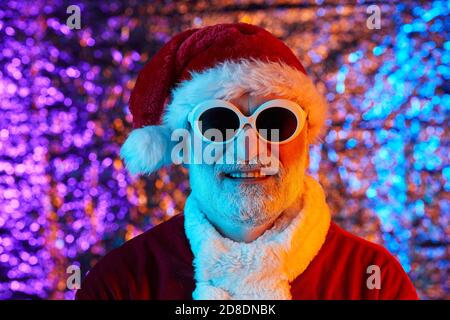 Ritratto di Babbo Natale in cappello con occhiali da sole sorridenti alla telecamera Foto Stock