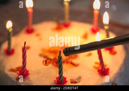 Closeup di una torta di anniversario decorata con candele che sono essere illuminato con un accendisigari Foto Stock
