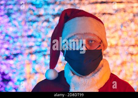Ritratto dell'uomo anziano in costume di Santa con maschera protettiva Festeggiamo il nuovo anno durante la pandemia Foto Stock