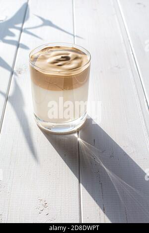 Bevanda tradizionale coreana con caffeina, caffè dalgona in un bicchiere trasparente su sfondo bianco. Latte e caffè montato. Un rinvigorente br Foto Stock