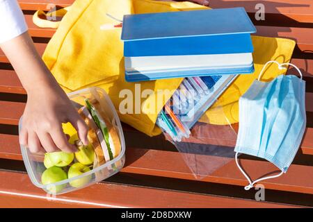 Pranzo al sacco, mani del bambino. Panini con pane, cetriolo, salsiccia, mele in un contenitore di plastica. Colazione scolastica, pranzo. Ritorno a scuola. Brea pranzo Foto Stock
