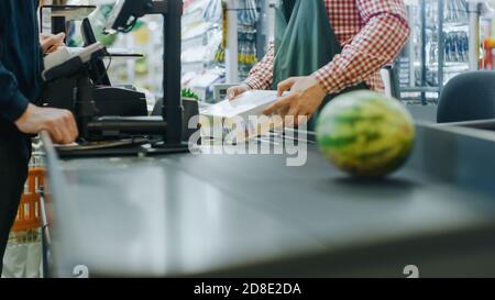 Al supermercato: Cassa mani del cassiere scansiona generi alimentari, frutta e altri prodotti alimentari sani. Centro commerciale pulito e moderno con Foto Stock