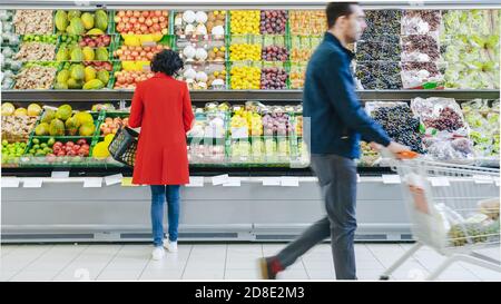 Al supermercato: La donna sceglie frutta biologica nella sezione prodotti freschi del negozio. Lei Picks up Cantaloupe e li mette nel suo Shopping Foto Stock