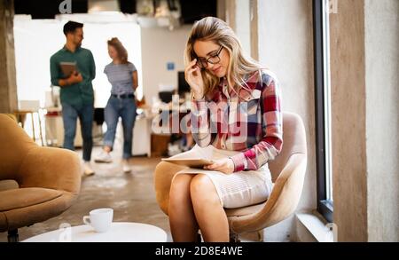 Donna di affari con un tablet, i suoi colleghi discutono di questioni aziendali in background Foto Stock