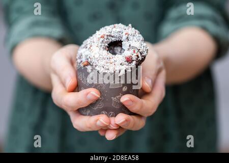 Colpo di primo piano di una donna che tiene le ciambelle vegane crude dentro una tazza Foto Stock
