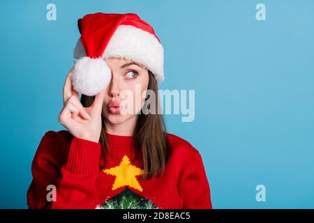 Foto ritratto di giovane ragazza millenaria che indossa cappellino di natale che tiene tenendo in mano il morbido batuffolo di cotone bianco guardando il lato con labbri a rilievo Foto Stock