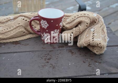 Coppa rossa o borgogna con un modello di fiocchi di neve sullo sfondo di una foresta invernale. Nevicare. Capodanno. Natale. Tazza con una bevanda calda sul Foto Stock