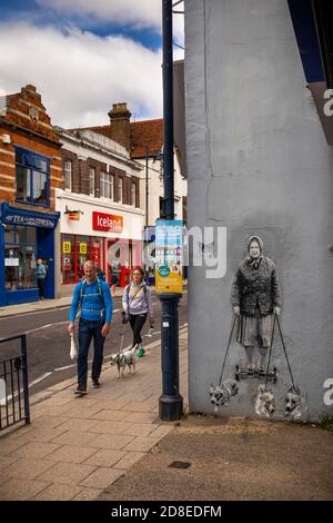 Regno Unito, Kent, Whitstable, High Street, camminatore di cane che passa accanto alla regina a piedi cani di strada arte da catman Foto Stock