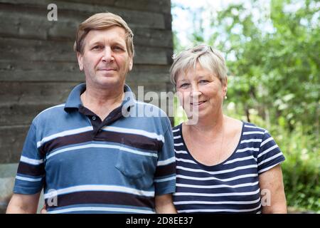 Caucasian senior coppia in piedi insieme in estate giardino cottage agaist, persone che guardano la macchina fotografica Foto Stock