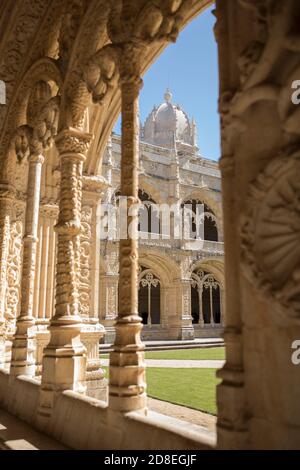 Architettura e archi decorati manuelini con vista sul campanile a cupola nel chiostro del Monastero di Jerónimos a Lisbona, Portogallo, Europa. Foto Stock