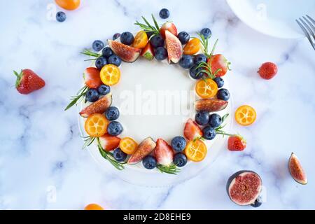 Vista dall'alto sulla torta di compleanno alla vaniglia decorata con frutti di bosco: Fragole, mirtilli, fichi su sfondo marmoreo. Festa, torta di festa. Torta Foto Stock