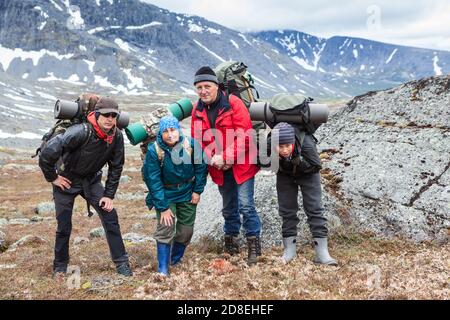 Escursionisti che respirano pesantemente con grandi zaini in piedi sul passo di montagna, quattro persone hanno un tour di arrampicata Foto Stock