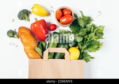 Borsa di carta con diversi alimenti freschi sani su sfondo bianco, piatto. Foto Stock