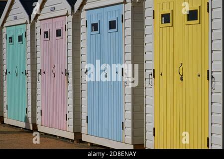 Lyme Regis, Dorset e le porte in legno di colore pastello tenue adornano capanne sulla passeggiata lungomare. Foto Stock