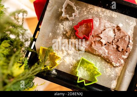 Colpo dettagliato di biscotti di pan di zenzero pasta e taglierina di biscotti di plastica su piano di lavoro in legno Foto Stock