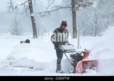 Un anziano, un bambino boomer, indossando la protezione dell'orecchio e gli scarponi da neve, la neve che soffia la strada a Chicago durante un vortice polare del wintry. Foto Stock