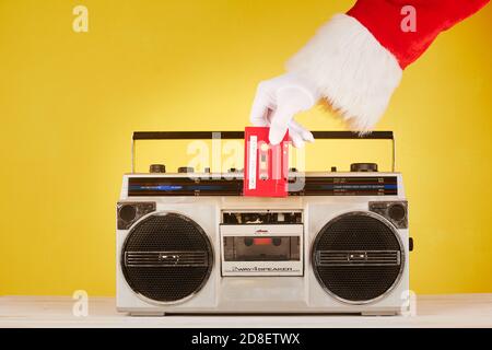 Mano di Babbo Natale che mette un nastro audio su una radio cassetta Foto Stock