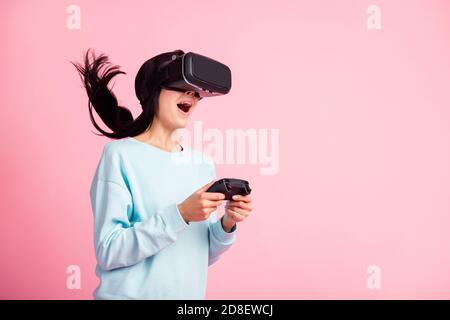 Foto di donna che usa occhiali vr 3d effetto di realtà sorprendente giocare giochi joystick indossare pullover isolato sfondo rosa Foto Stock