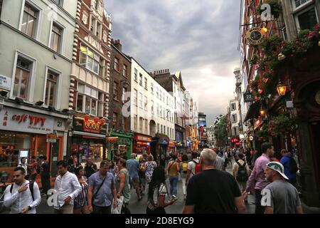 Inghilterra, Londra - Agosto 2018. Vita cittadina nel quartiere di Soho. I turisti e la gente del posto affollano una strada durante un estate tardo pomeriggio. I cartelli del pub sono già Foto Stock